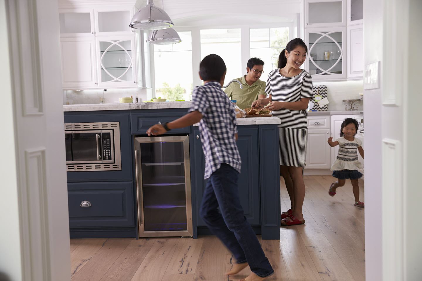 Woman in kitchen with three kids running around her